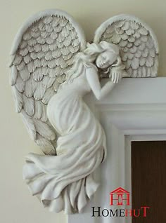 an angel figurine sitting on top of a white mantle next to a door