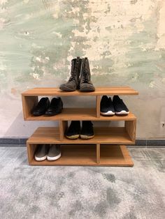 two wooden shelves with shoes on them in front of a wall