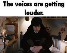 a man sitting on top of a bed next to a lamp and a sign that says, the voice are getting louder