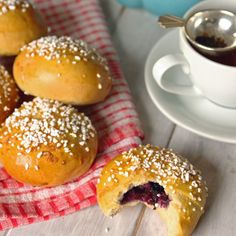 pastries with powdered sugar sit on a napkin next to a cup of tea