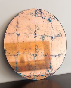 a round metal plate sitting on top of a wooden table next to a white wall