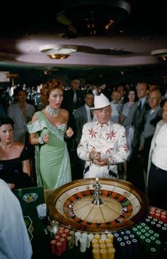 a man and woman standing in front of a roule on a table surrounded by other people