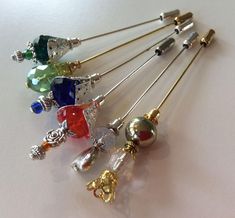 six different colored jeweled hair pins on a white surface