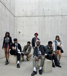 a group of people sitting next to each other in front of a cement wall,