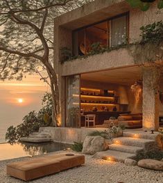 a house that is next to the ocean with lights on it's windows and stairs