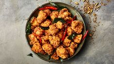 a plate full of fried food with red peppers and seasoning on the table next to it