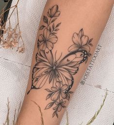 a woman's arm with a butterfly and flowers tattoo design on the left forearm