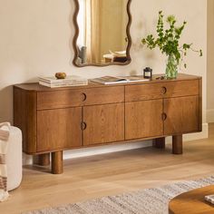 a wooden dresser sitting in front of a mirror on top of a wall next to a plant