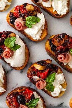 several pieces of bread with various toppings on them sitting on a marble counter top