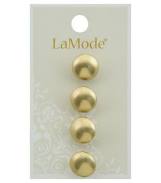 three gold colored metal buttons in front of a white card with the word lamode on it