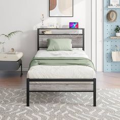 a bed sitting on top of a wooden floor next to a wall with pictures above it