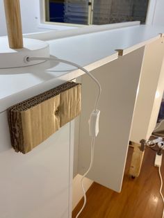 an electrical cord is plugged in to the side of a white cabinet with a mirror behind it