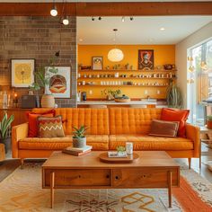 a living room with an orange couch and coffee table in front of a brick wall