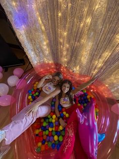 two girls are in an inflatable ball pit