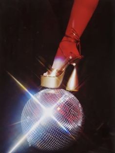 a person's feet in high heels on top of a disco ball with lights