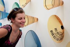 a woman standing in front of a wall with many hats on it