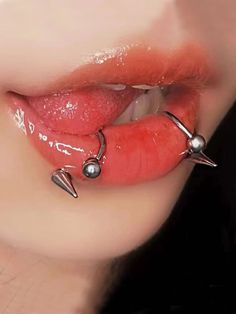 a woman's tongue with piercings on it and two balls attached to the lip