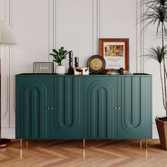 a green cabinet with gold legs and a clock on it's sideboard next to a potted plant