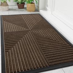 a door mat on the floor in front of a potted plant