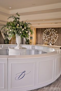 a large white vase with flowers on top of it in front of a reception counter