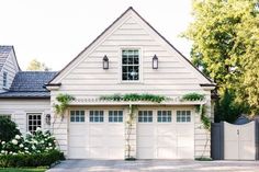 a white house with two garage doors and windows