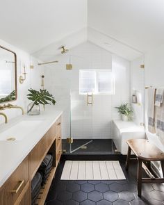 a bathroom with white walls and black flooring is shown in this image, there are two sinks on the opposite side of the bathtub