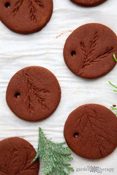 chocolate cookies decorated with leaves and sprigs on a sheet of waxed paper