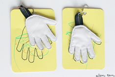 two pairs of white gloves on top of a yellow piece of paper with scissors attached to them