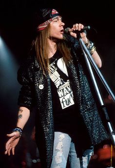 a woman with long hair and piercings on her head holding a microphone while standing in front of a crowd