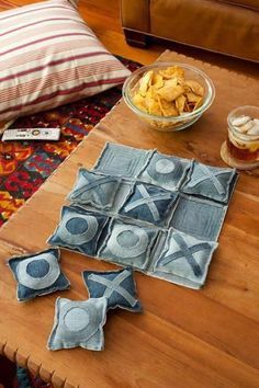 a wooden table topped with blue pillows and bowls of food next to a brown couch