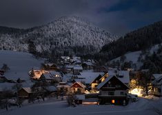 a snowy mountain town with houses lit up at night