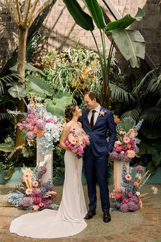 a bride and groom standing next to each other in front of an arch decorated with flowers