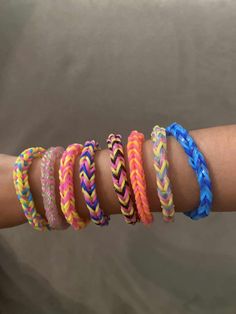 five different colored bracelets on someone's arm with one being held in the other hand