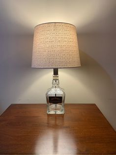 a lamp that is sitting on top of a wooden table next to a glass bottle