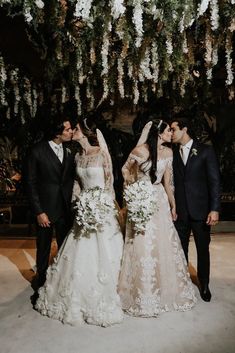 the bride and grooms are kissing in front of an artificial flower wall at their wedding