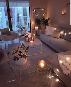 a living room filled with white furniture and lots of candles on the table next to it