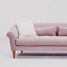 a pink couch with two white pillows on it's back and the seat upholstered