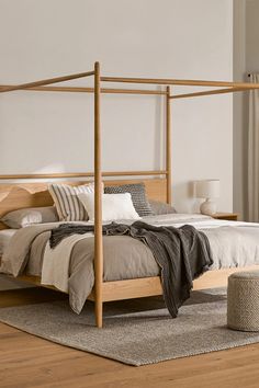 a wooden bed frame in a bedroom with white walls and wood flooring, along with a rug on the floor