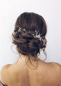 the back of a woman's head wearing a bridal hair piece with flowers in it