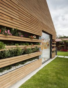 the side of a wooden building with plants growing on it's sides and windows