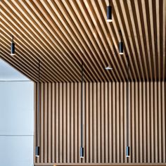 an empty bench in the middle of a room with wooden slats on the ceiling