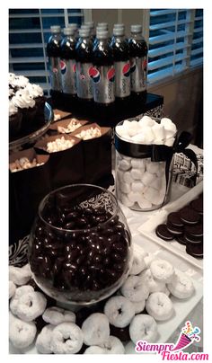 a table topped with lots of different types of donuts next to bottles of soda