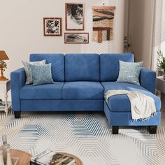 a blue couch sitting in a living room next to a lamp and pictures on the wall