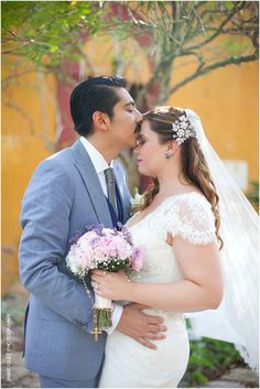 a bride and groom kissing in front of trees