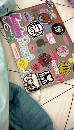 a laptop computer sitting on top of a bed covered in stickers