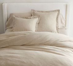 an unmade bed with beige linens and pillows