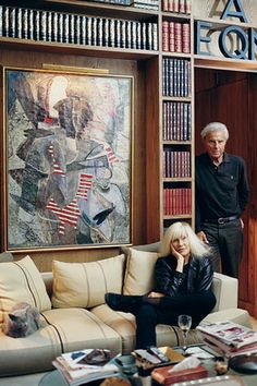 a man and woman standing next to each other in a room with bookshelves