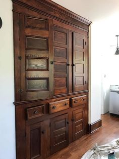 a large wooden cabinet sitting on top of a hard wood floor next to a wall