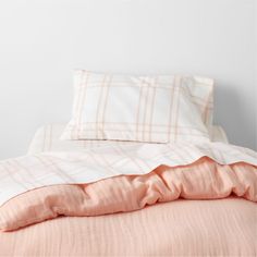 an unmade bed with pink sheets and pillows