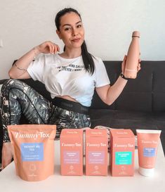 a woman sitting on a couch with five different types of skin care products in front of her